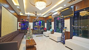 A modern lobby with a chandelier, sofas, a Christmas tree, and a reception desk.