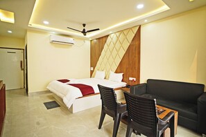 Habitación de hotel con cama, escritorio, silla, sofá y ventilador de techo.
