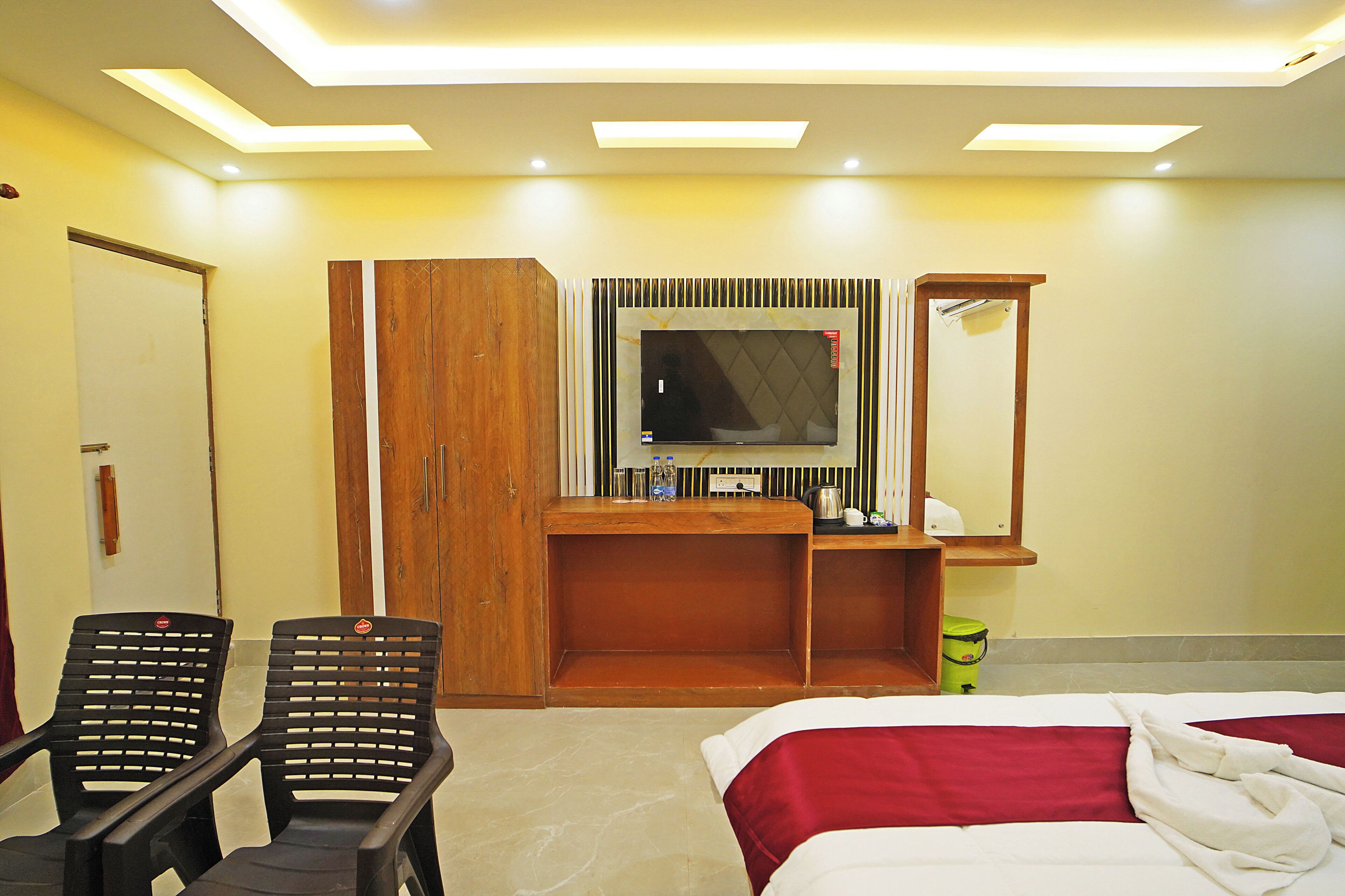 Une chambre d’hôtel comprenant un lit, un bureau avec un téléviseur à écran plat, deux chaises, une armoire en bois et un miroir.