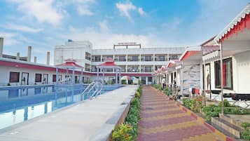 A hotel with a swimming pool, a covered walkway, and a building with balconies.