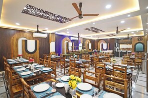 Un restaurante con varias mesas, sillas de madera, ventiladores de techo y paneles decorativos en la pared.