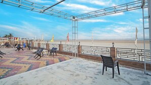 A beachside terrace with seating and a view of the beach.