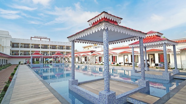 A resort with a swimming pool, covered seating areas, and a building labeled 'UNIQUE BEACH RESORT'.