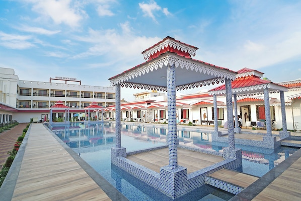 Un resort con piscina, zonas de estar cubiertas y un edificio que dice 'UNIQUE BEACH RESORT'.