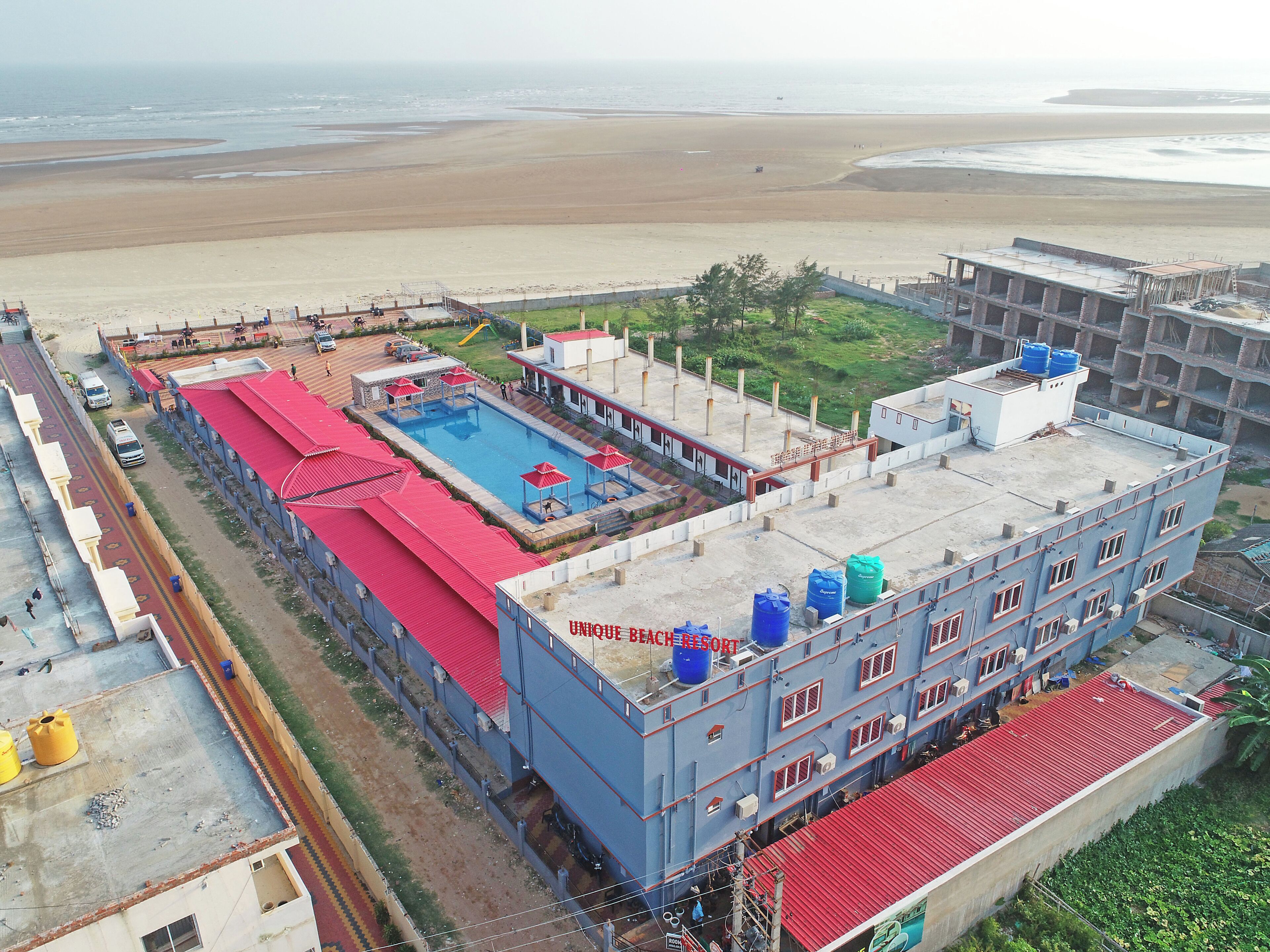 Un bâtiment doté d’une piscine, offrant une vue sur la plage et caractérisé par une structure surmontée d’un toit rouge.