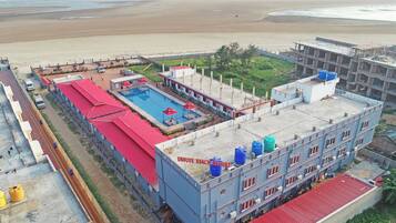 A building with a swimming pool, a beach view, and a red-roofed structure.