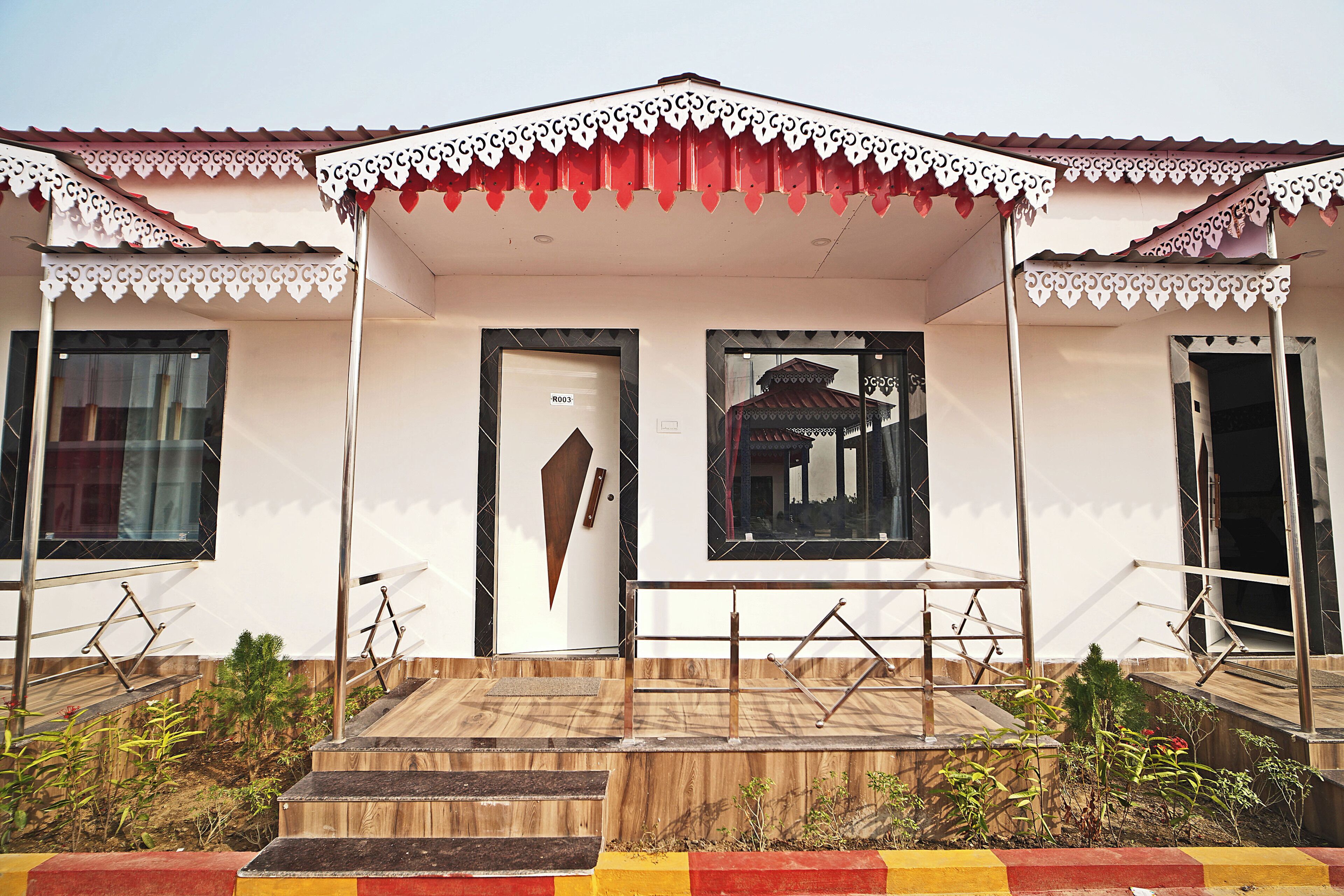 A building with a white facade, a central door with a sign, and a small porch with steps leading up to it.