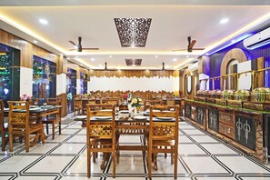 Un restaurante amplio con varias mesas y sillas, ventiladores de techo y paneles decorativos en las paredes.