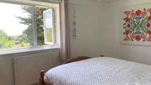 Een slaapkamer met een enkel bed, een raam met gordijnen, een radiator en een decoratie aan de muur.