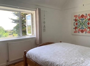 A bedroom with a single bed, a window with curtains, a radiator, and a wall-mounted decoration. - Seaford 1-bed House Sleeps 2, Sea Views & Parking (Seaford)