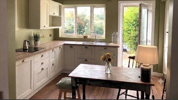 Een keuken met een houten tafel, een gootsteen en een raam met uitzicht op groen.