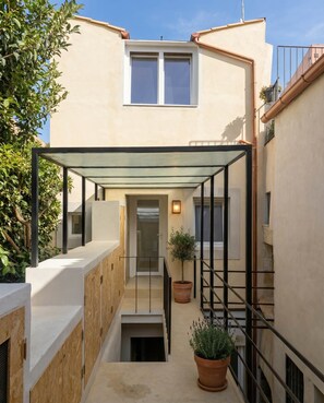 A narrow outdoor corridor with a glass enclosure, wooden steps, and potted plants. - Casa Mille e una Stella: Rooftop Terrace & Open-Sky-Room (Siracusa)