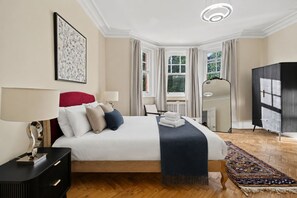 A hotel room with a large bed, a desk, a chair, a wardrobe, and a view of the outdoors. - Holland Park 5BR 3BA Stay With Private Sauna (London)