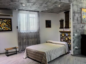 A bedroom with a bed, a bench, a wall with decorative plates, and a painting. - Cycas Loft - Misilmeri (Misilmeri)