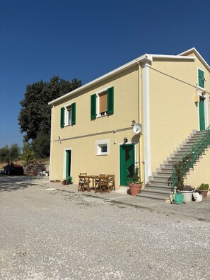 Un edificio di due piani con una scala, un'antenna parabolica e mobili da esterno.