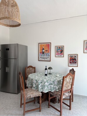 Een eetgedeelte met een tafel voor twee personen, een koelkast, en wanddecoratie.