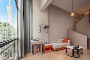 A modern hotel room with a large window, a sofa, a small table, and a nightstand.