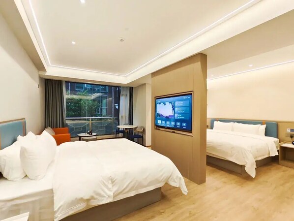 A hotel room with two beds, a TV, a balcony, and a small table with chairs.