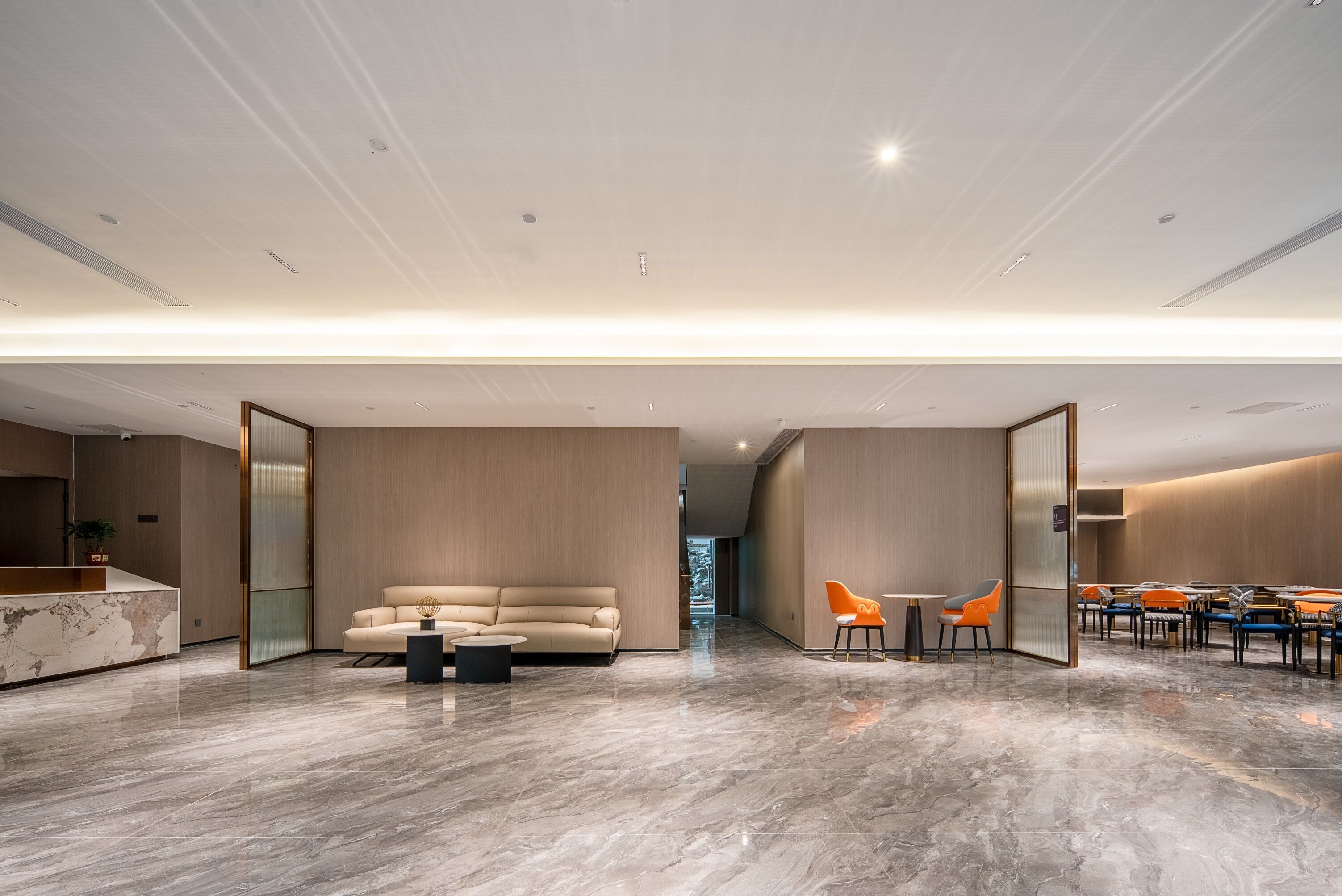 A modern interior with a marble floor, a sofa, a coffee table, and a dining area with chairs.