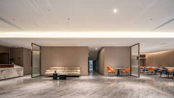A modern interior with a marble floor, a sofa, a coffee table, and a dining area with chairs.
