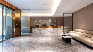 A modern hotel lobby with a marble reception desk, a sofa, and a coffee table.