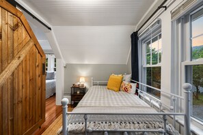 Un dormitorio con una cama, una mesita de noche, una lámpara y una ventana.