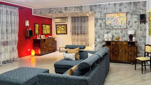 Una sala de estar con un sofá gris, un mueble de madera y obras de arte en las paredes.
