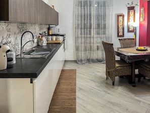 Una cocina moderna con microondas integrado, un lavamanos y un comedor con mesa y sillas.