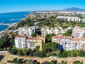 A coastal residential area with apartment buildings, a beach, and a mountain in the background. - 1 Dormitorio Andalucia del Mar Ref 209 (Marbella)