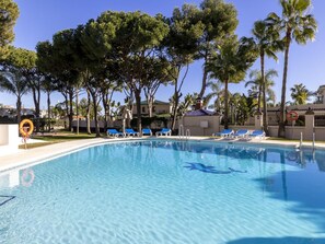 A swimming pool with clear blue water, surrounded by lounge chairs and palm trees. - 2 Dormitorios Andaluc a del Mar Ref 316 (Marbella)