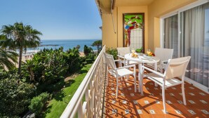 Ein Balkon mit Tisch für zwei Personen, Blick auf einen Strand und das Meer.