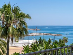 A coastal view with a lighthouse, rocky breakwaters, and palm trees. - 2 Dormitorios Andaluc a del Mar Ref 316 (Marbella)