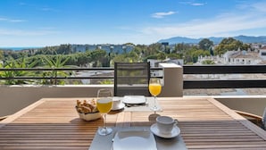 Ein Tisch ist für das Frühstück gedeckt, mit Blick auf eine Stadtlandschaft und Berge.