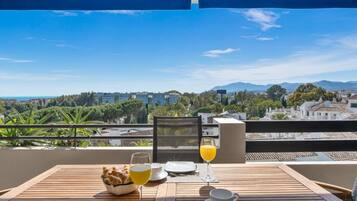 Una mesa dispuesta para el desayuno con vistas a un paisaje urbano y montañas.
