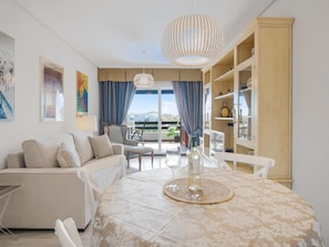 Ein modernes Wohnzimmer mit einer Couch, einem Esstisch und Blick ins Freie.