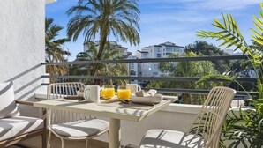 A balcony with a table, chairs, and a view of palm trees and buildings. - Acogedor Estudio en Medina Garden ref 122 (Marbella)