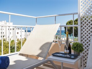 Ein Balkon mit Liegestuhl, einer Weinflasche und einem Tablett mit Gläsern.