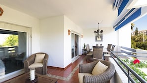 A balcony with wicker furniture, a dining table, and a chandelier. - 2 Dormitorios Medina Garden Ref 623 (Marbella)