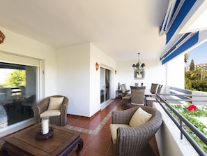 A balcony with wicker furniture, a dining table, and a chandelier. - 2 Dormitorios Medina Garden Ref 623 (Marbella)