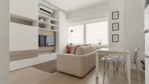 A modern living room with a sofa, a dining table with chairs, a flat-screen TV, and a fireplace. - GuestHost - Cozy Apartment in Darsena, Near the Navigli (Milan)