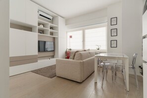 Uma sala de estar moderna com sofá, mesa de jantar e cadeiras, televisão de tela plana e lareira.