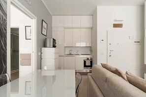 A modern kitchen with white cabinets, a stainless steel oven, and a coffee machine. - GuestHost - Cozy Apartment in Darsena, Near the Navigli (Milan)