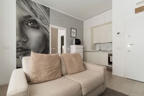 Sala de estar com sofá, cozinha e uma porta.