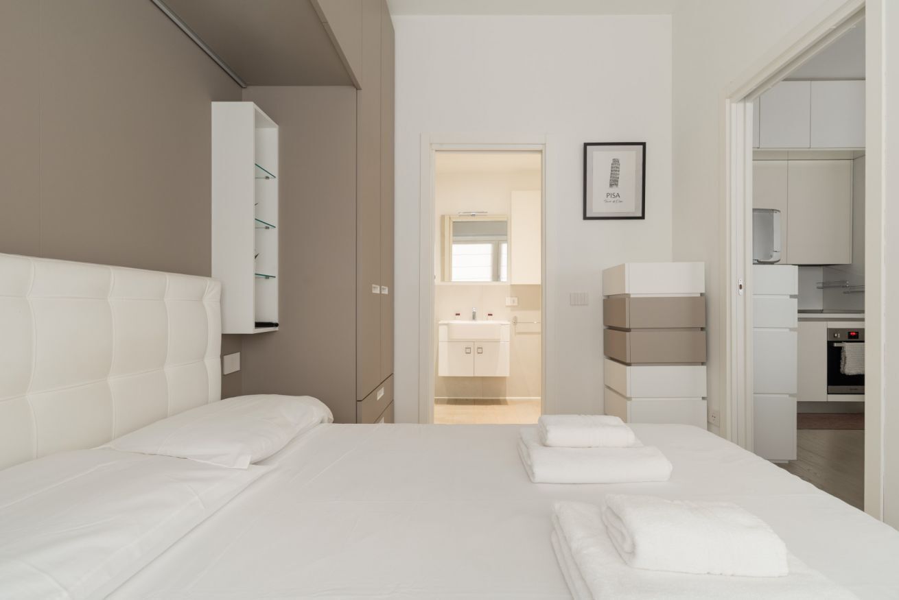 Ein Hotelzimmer mit Bett, Schrank, angrenzendem Badezimmer und einer Küchenzeile.