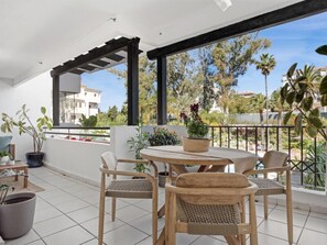 A balcony with a table and chairs, potted plants, and a view of the surrounding area. - Apartamento en Medina Garden Ref 611 (Marbella)
