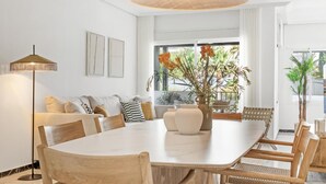 Uma sala de jantar moderna com uma grande mesa de madeira, cadeiras de fibra e um lustre.