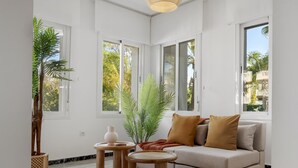 Uma sala de estar moderna com um sofá, duas mesinhas laterais e uma janela grande.