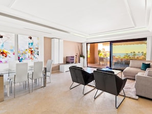 Ein geräumiges Wohnzimmer mit Balkon, Essbereich und Fernseher.