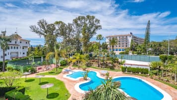 Un resort con piscina, exuberante vegetación y cielo azul despejado.