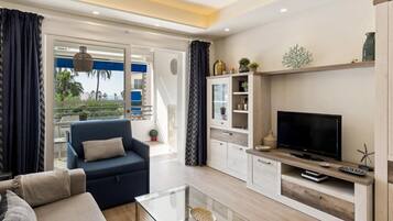 Una sala de estar moderna con sofá, televisor, una mesa de centro de vidrio y estanterías empotradas.